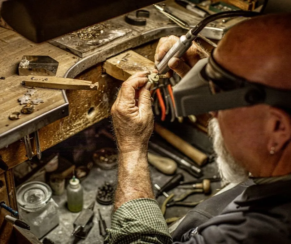 Welding a silver ring with a flame, showcasing jewelry repair craftsmanship.