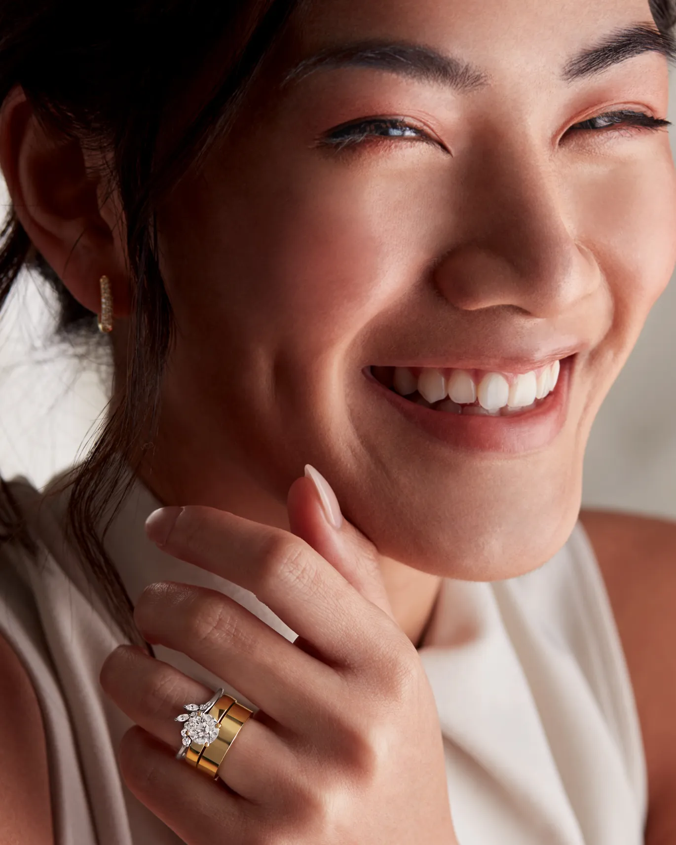 Smiling woman showcasing elegant gold and diamond rings.