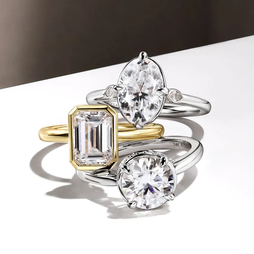 Three elegant lab-grown diamond rings featuring different cuts and settings, displayed on a sleek surface.