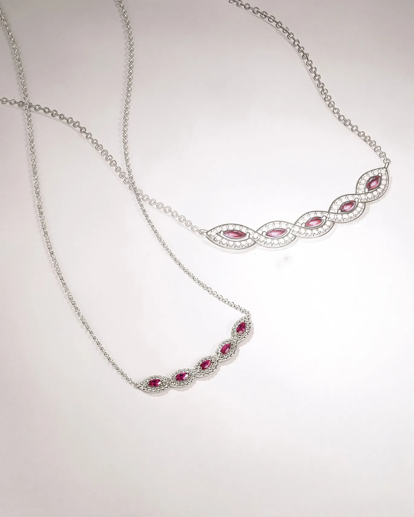 Two elegant silver necklaces with pink gemstones, one with a wavy design, displayed on a light background.
