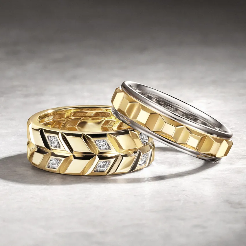 Two elegant wedding bands, one gold with diamonds and one silver, displayed on a textured surface.