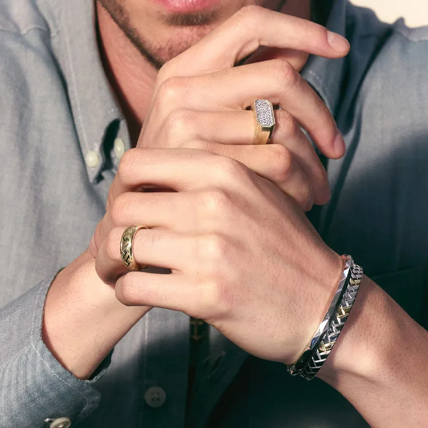 Close-up of a man's hands showcasing various rings and bracelets.