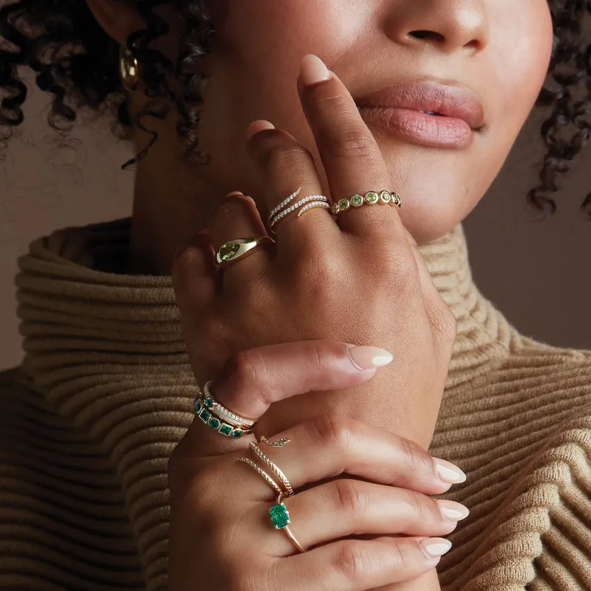 Elegant rings displayed on a woman's hand, showcasing various styles and gemstones.