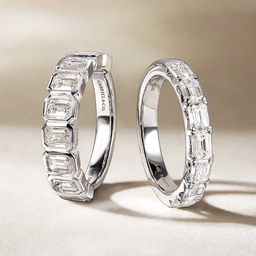Two elegant wedding bands featuring emerald-cut diamonds set in polished white gold. 