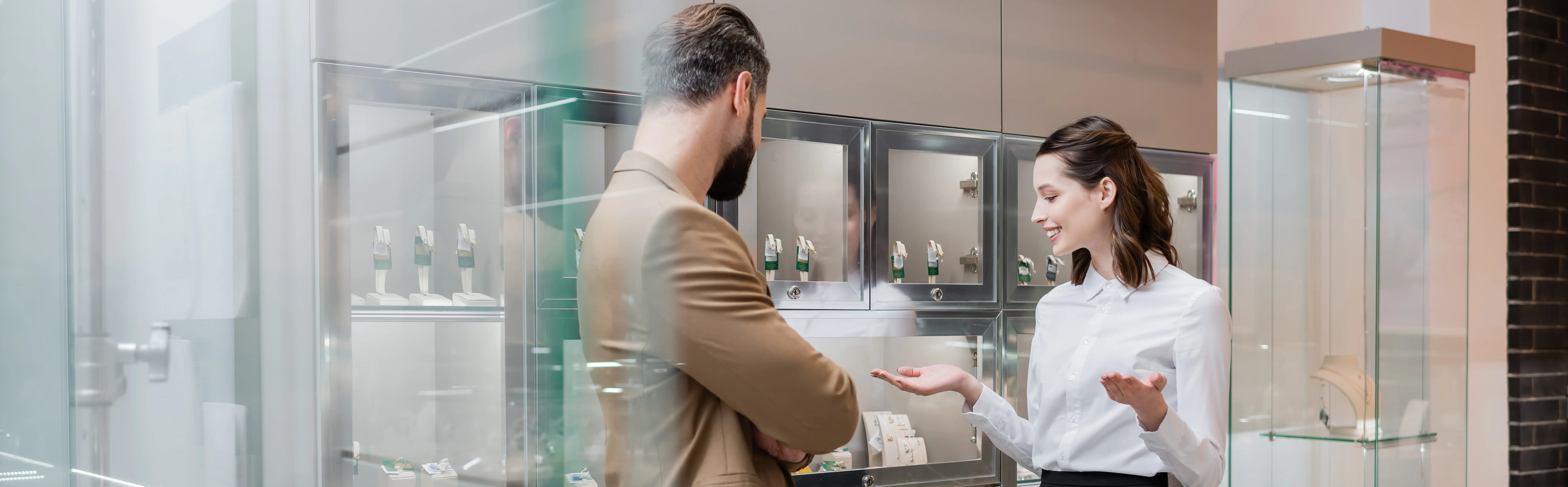 A jewelry store employee assists a customer, showcasing fine jewelry in a display case at The Blue Diamond in Jefferson City.