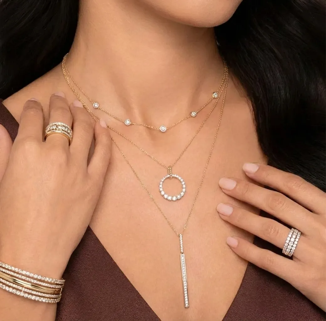 Close-up of a woman wearing elegant jewelry: a necklace, earrings, and rings, showcasing fine craftsmanship.