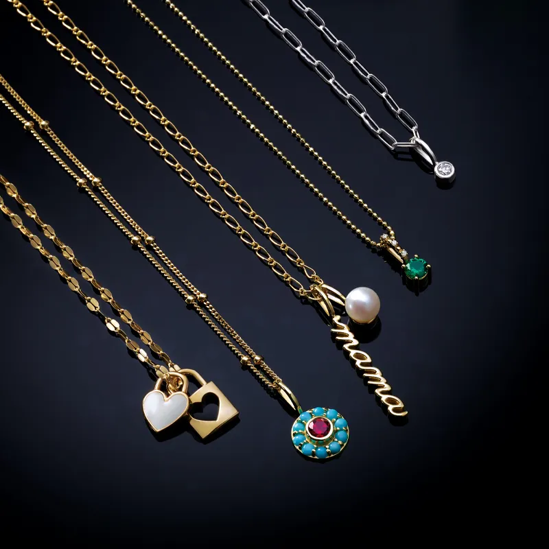 Gold and silver necklaces with charms, including hearts, a pearl, and 