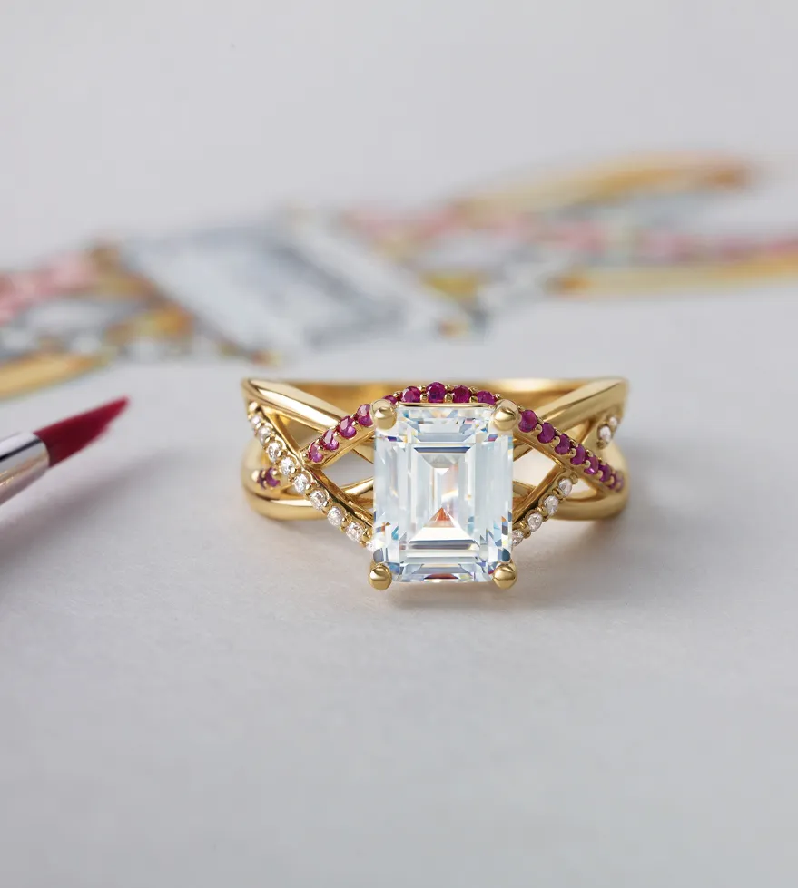 Elegant gold ring with an emerald-cut center stone, accented by rubies and diamonds. Visit The Diamond Shop, Inc. for more.