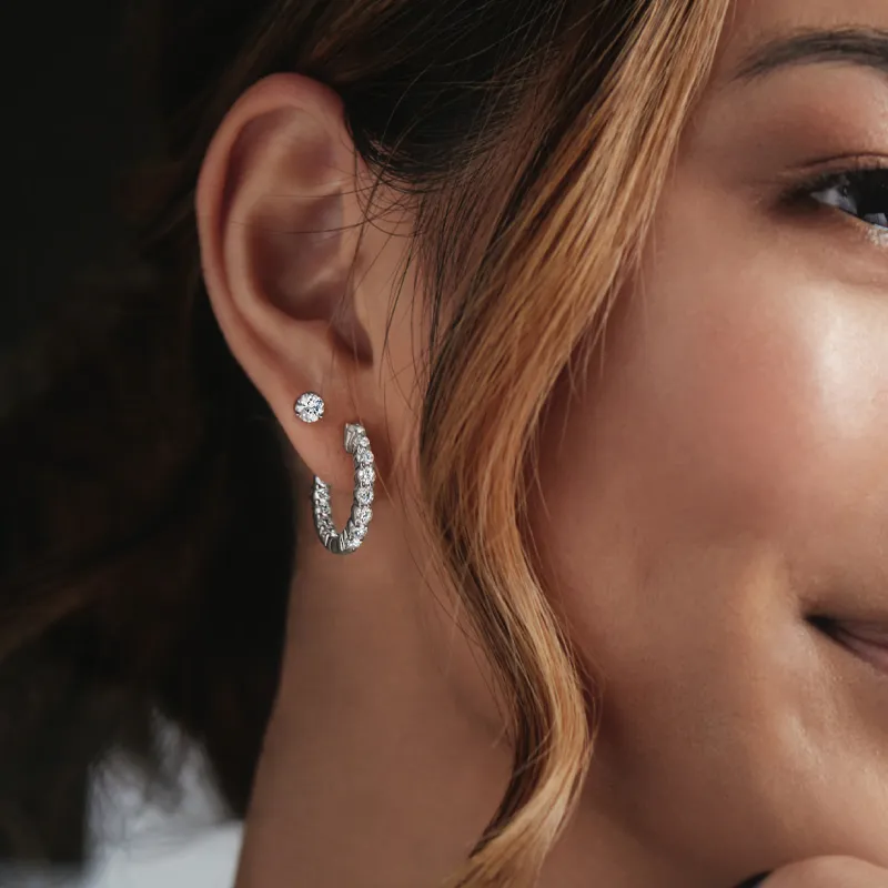 Close-up of a woman's ear showcasing elegant diamond earrings. Click to shop now at The Diamond Shop, Inc. in Lewiston.