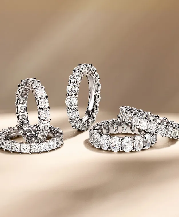 Five elegant diamond rings in various styles displayed on a soft background. Visit The Diamond Shop, Inc. for more.