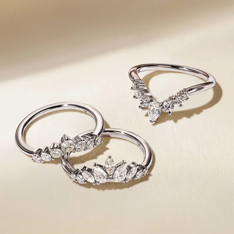 Three elegant diamond rings displayed on a soft surface.