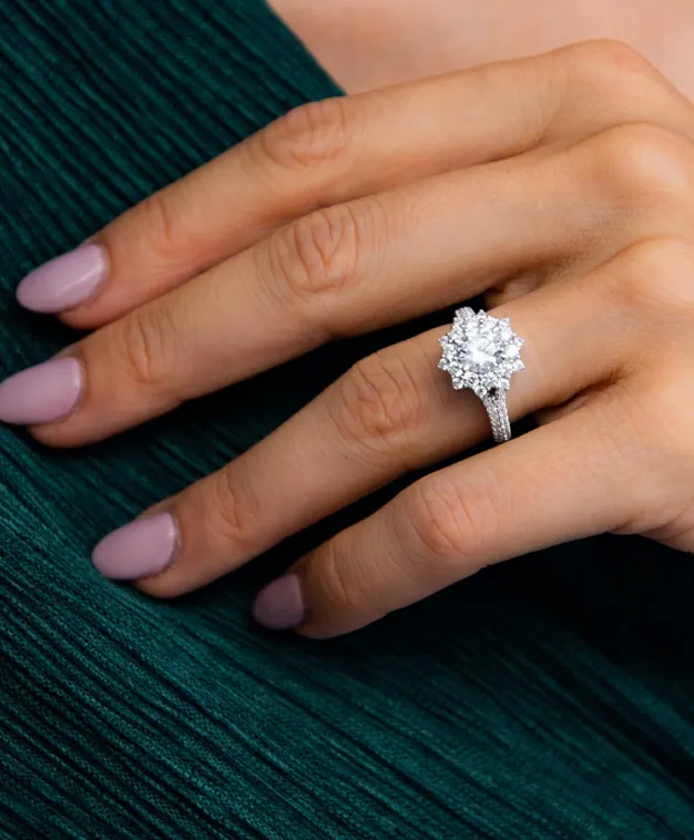 A hand wearing a stunning diamond engagement ring, showcasing intricate details and a sparkling centerpiece.