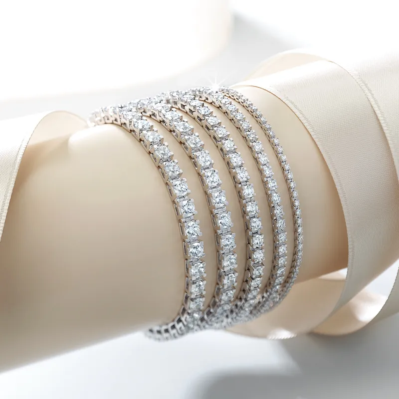 Four elegant tennis bracelets with sparkling diamonds displayed on a soft surface.