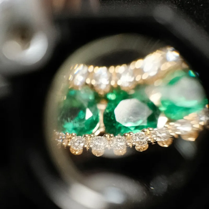 Close-up of emerald and diamond jewelry, showcasing intricate details. 