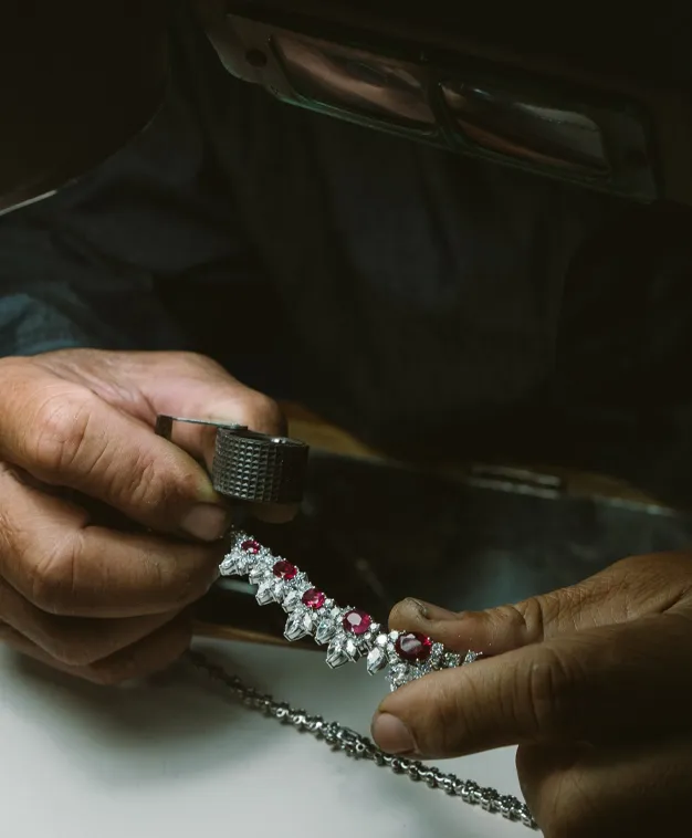 Jeweler inspecting a diamond and ruby bracelet under a magnifying glass at The Diamond Shop, Inc. in Lewiston.