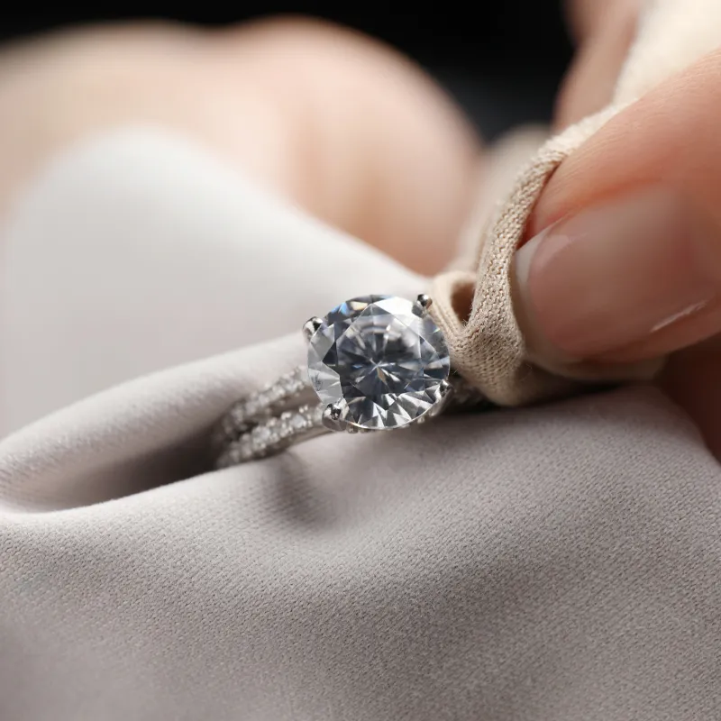 A hand polishing a sparkling diamond engagement ring on soft fabric.