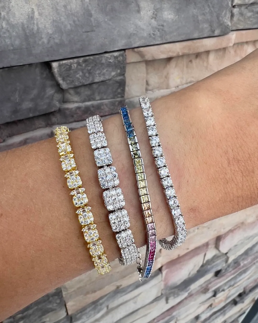 Elegant gold bracelet with a pear-shaped gray stone and sparkling diamonds, worn on a wrist against a green background.