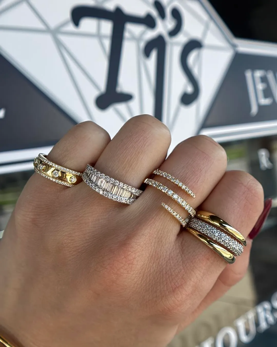 Elegant black diamond ring with a unique design, set against a blurred green background.