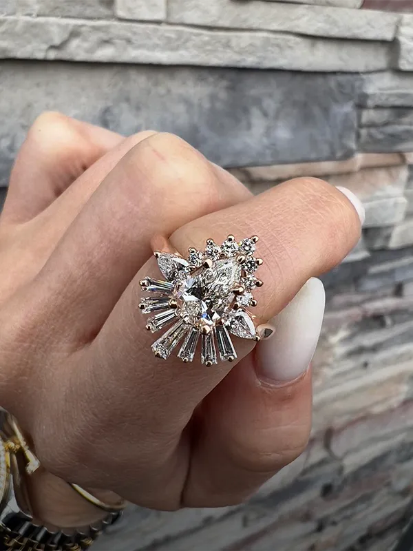 Vintage oval diamond ring with intricate detailing and smaller diamonds, set in rose gold.