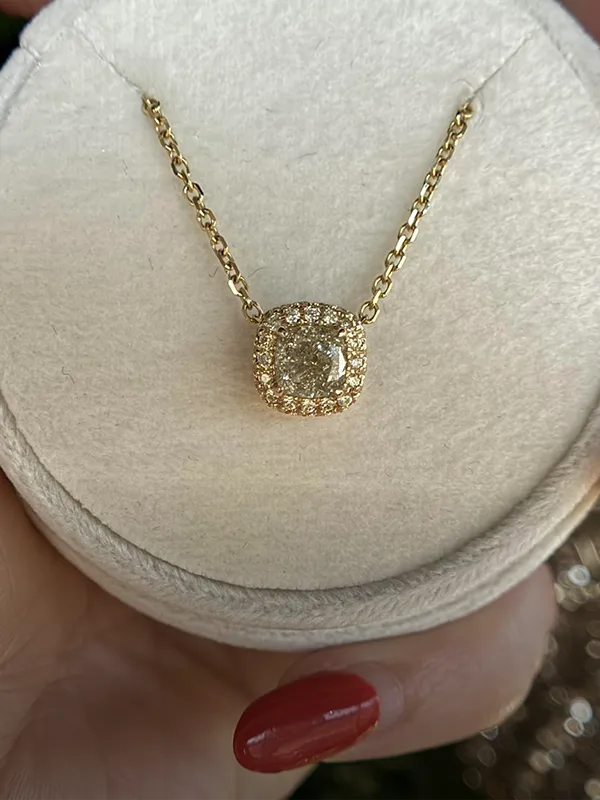 Close-up of a diamond necklace held in a hand, showcasing its sparkling stones.