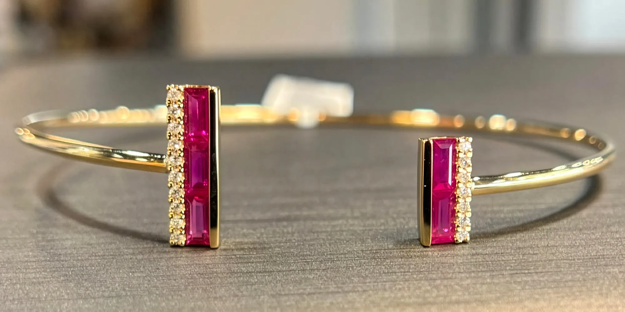 Gold bangle bracelet with pink gemstones and diamond accents, available at T.J.'s Fine Jewelry in Carbondale.