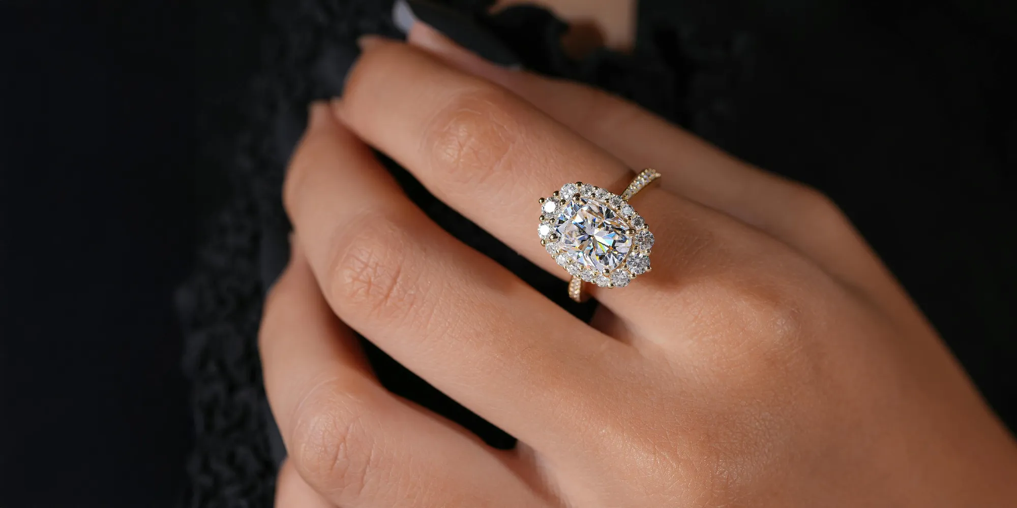 A hand wearing an elegant diamond ring with an oval center stone and surrounding smaller diamonds.