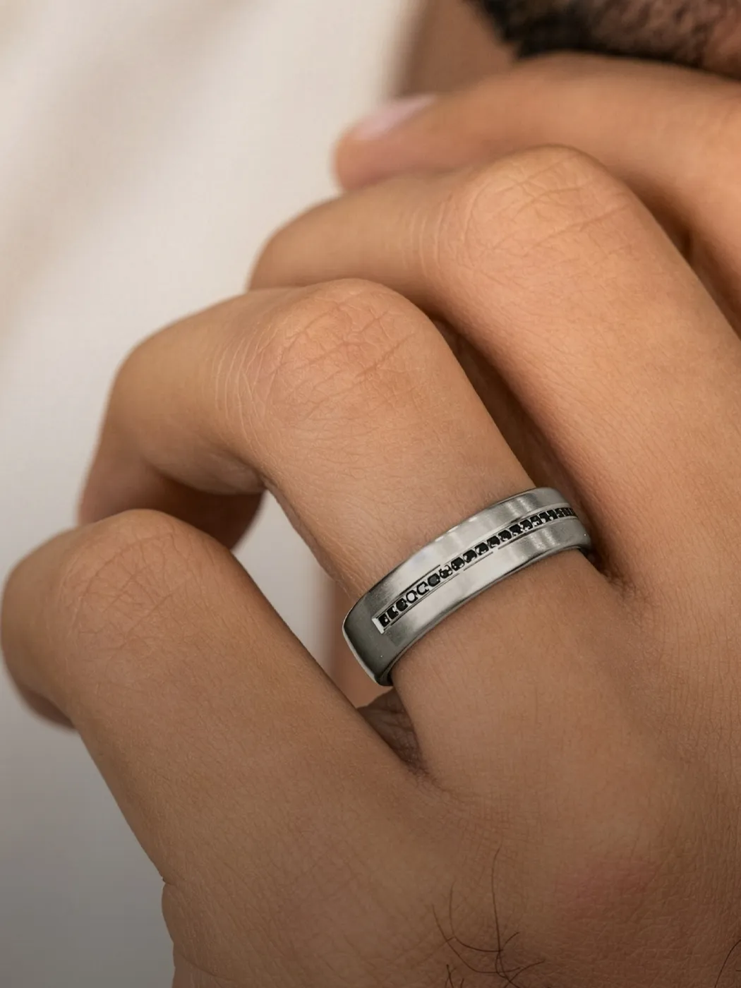 Men's wedding band displayed on a hand, showcasing a sleek design.