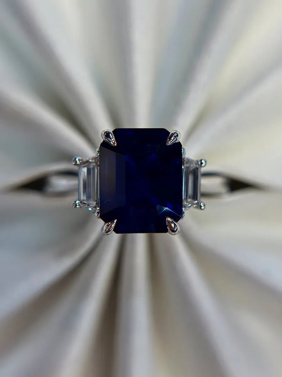 Elegant blue sapphire ring with side accents, displayed on a soft background.