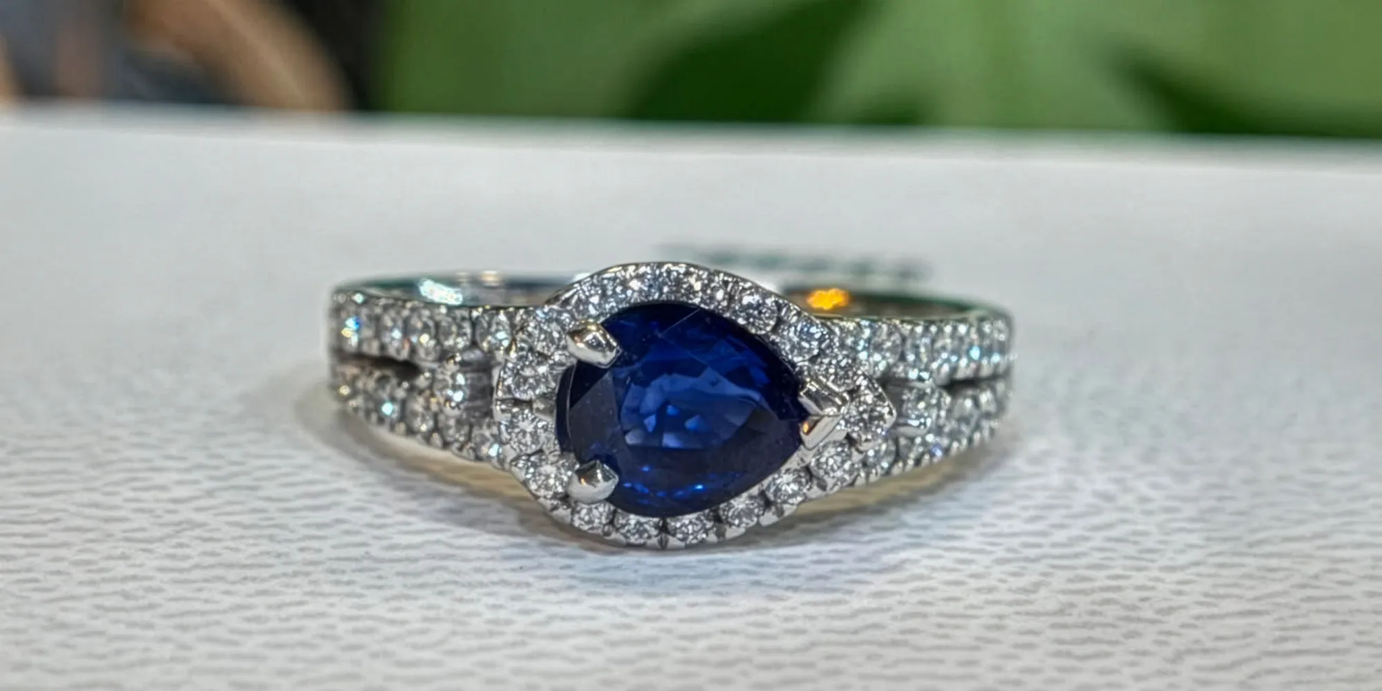 Elegant silver ring featuring a pear-shaped blue sapphire surrounded by sparkling diamonds.