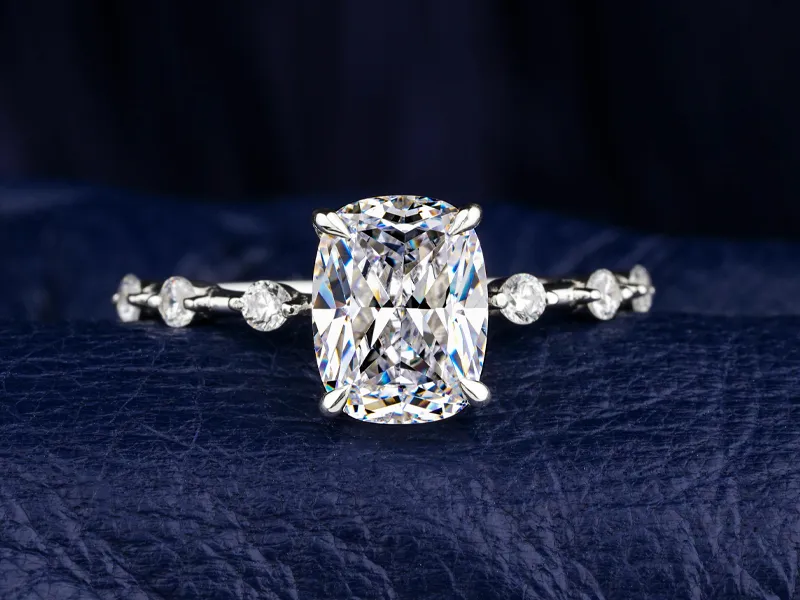Stunning cushion-cut diamond ring on a dark blue background, showcasing elegance and craftsmanship.
