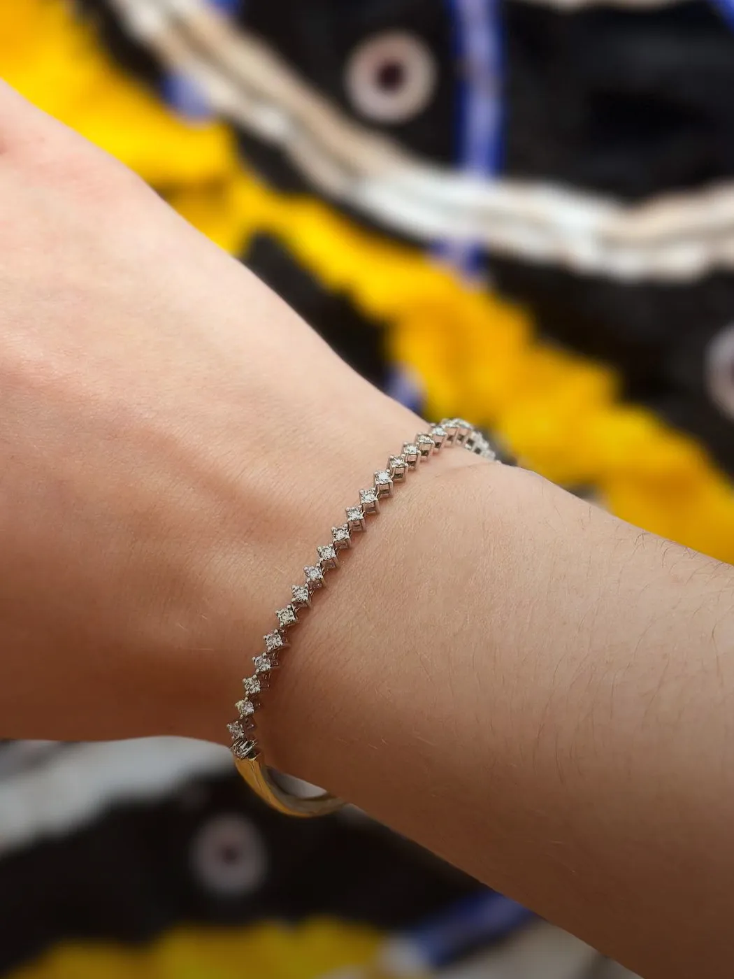 Diamond bracelet on a wrist, showcasing elegant design against a colorful background.