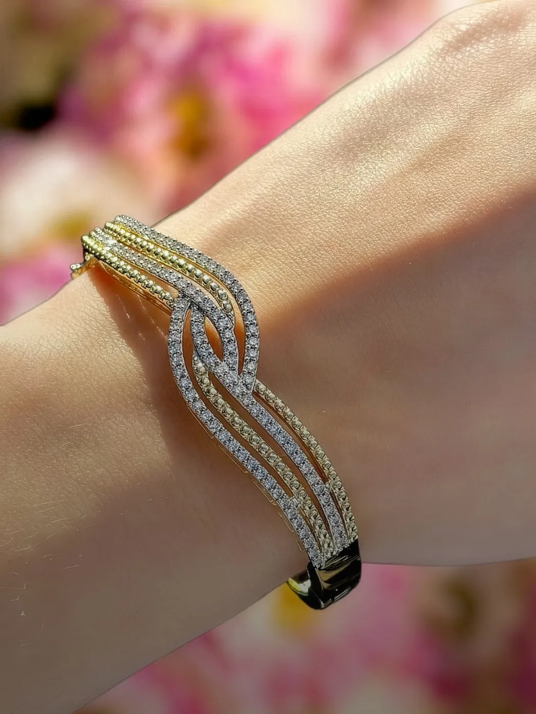 Elegant gold and diamond bracelet on a wrist, showcasing a stylish design.