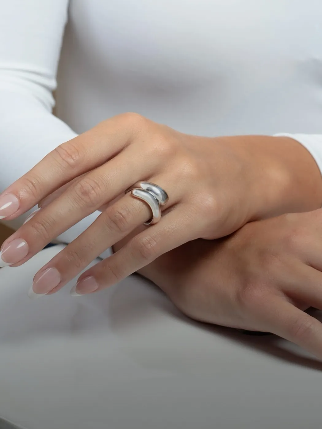 Stylish silver fashion ring worn on a hand with manicured nails.