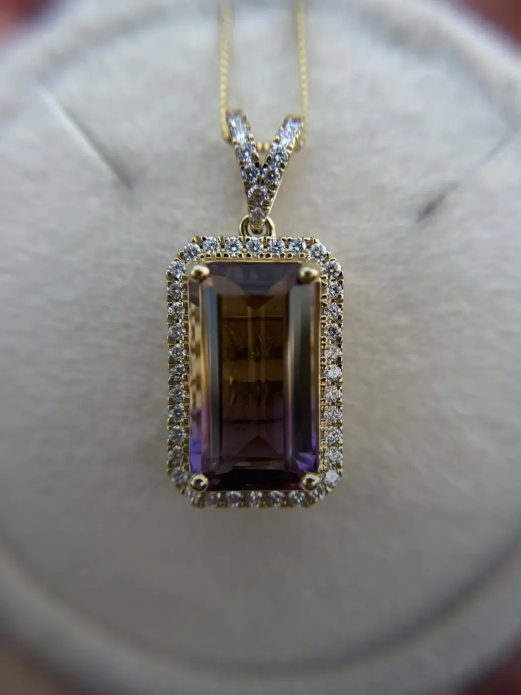 Elegant gemstone necklace featuring a large rectangular pendant surrounded by sparkling diamonds, set in gold.