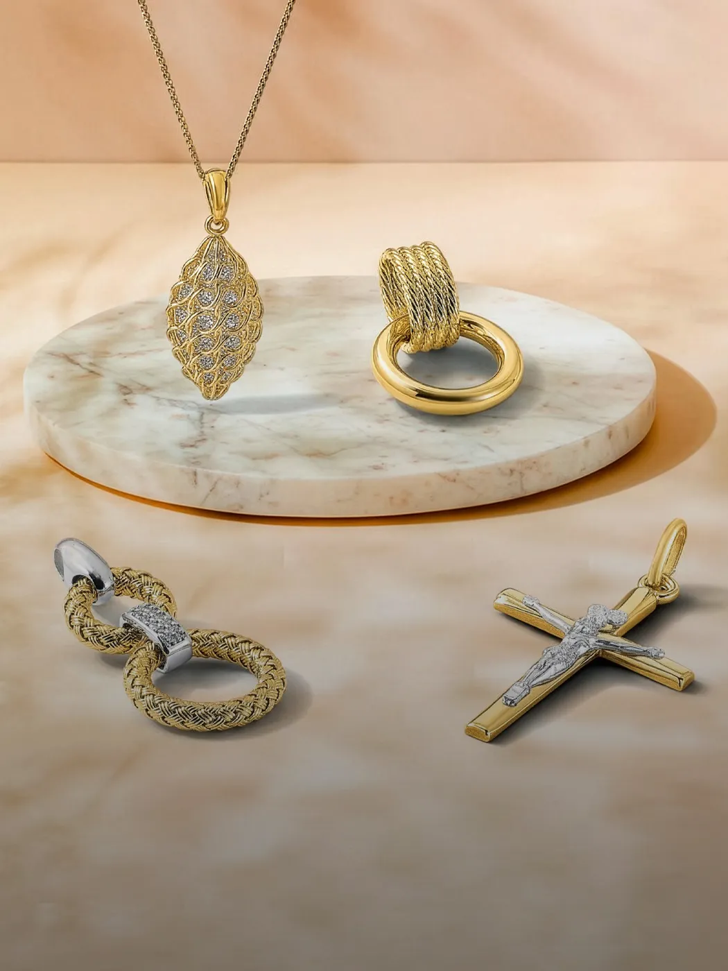 Gold and silver jewelry charms displayed on a marble surface.