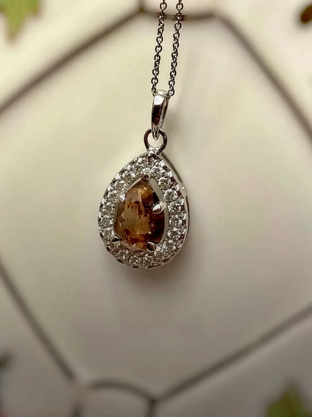 Elegant teardrop pendant necklace with a brown gemstone surrounded by sparkling diamonds.