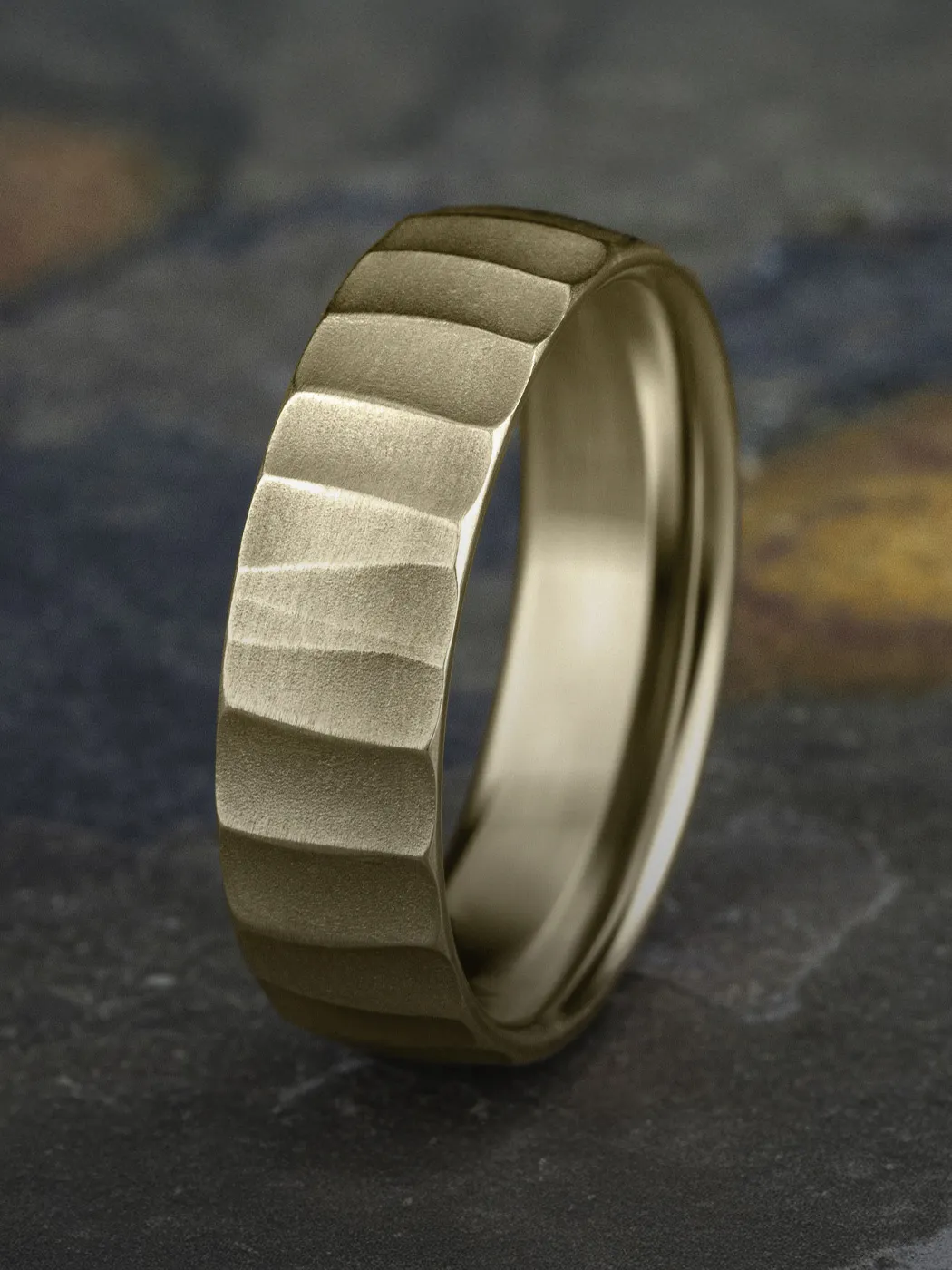 Textured gold wedding band displayed on a dark surface.