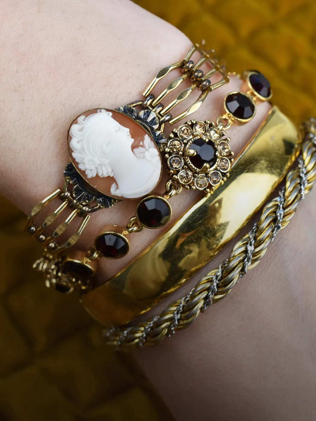 Elegant wrist adorned with vintage bracelets, featuring a cameo, gold accents, and black stones.
