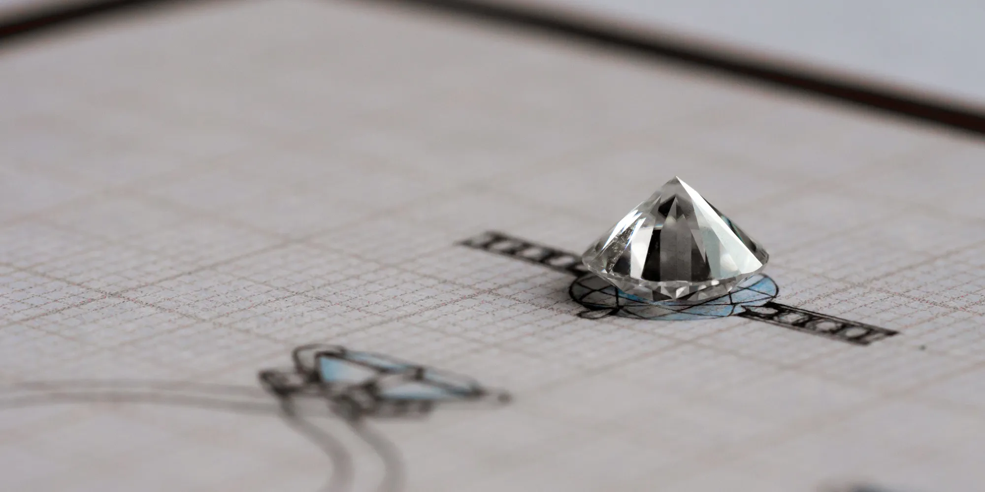 A diamond gemstone sits atop a design sketch for custom jewelry.