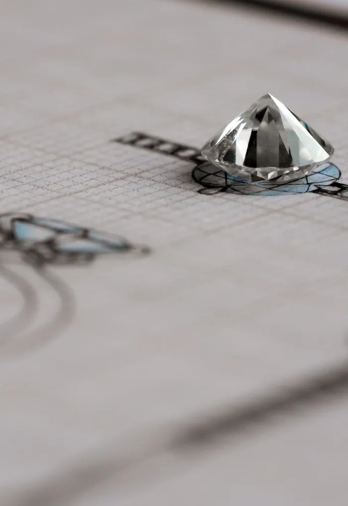 A diamond gemstone sits atop a design sketch for custom jewelry.