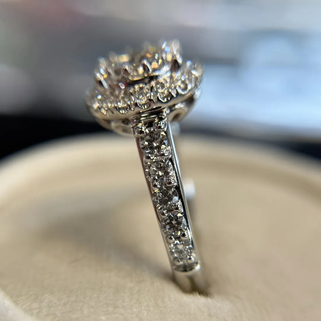 Close-up of a diamond-encrusted ring with a floral design, displayed on a soft surface.