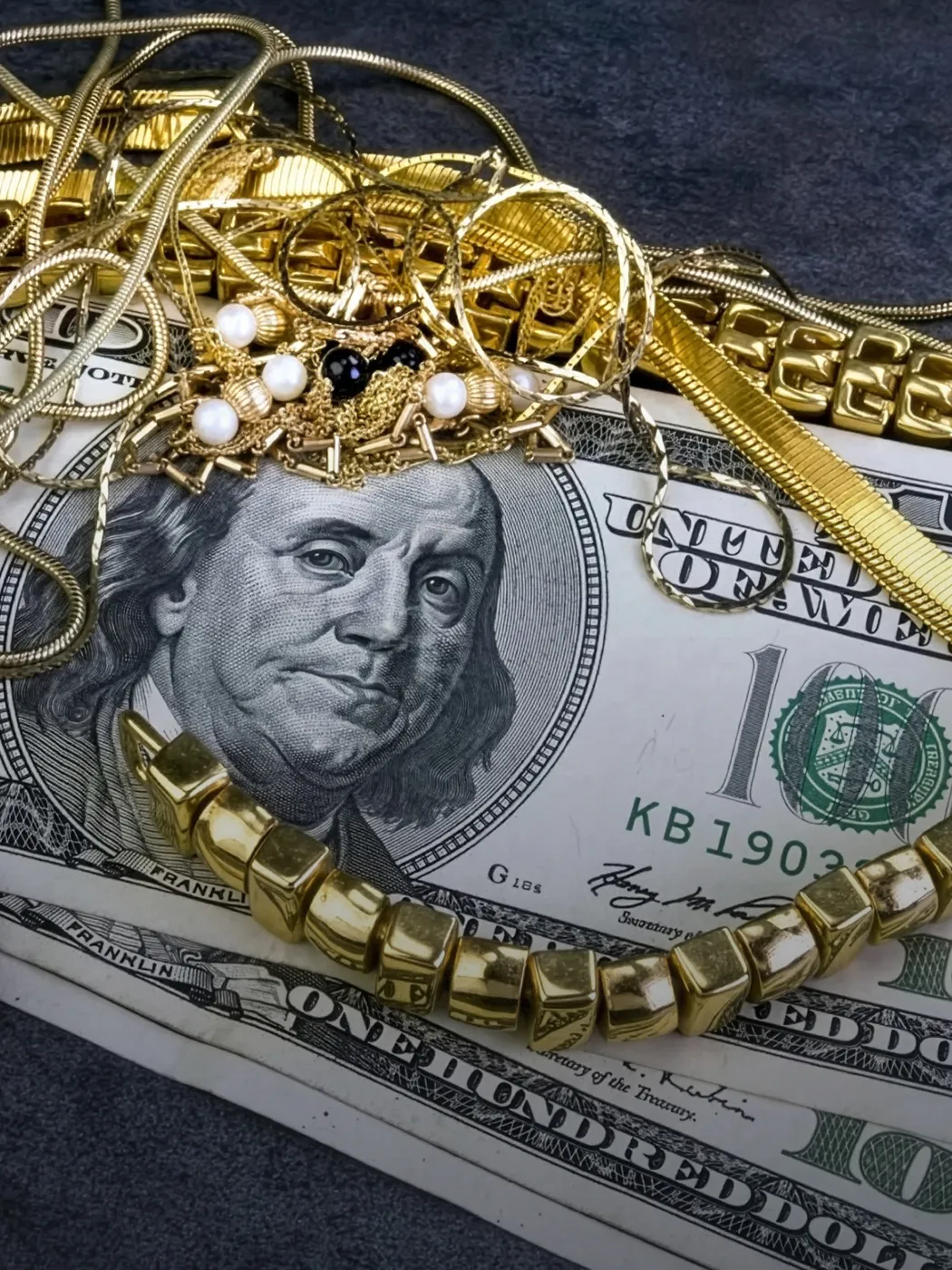 Gold jewelry and cash displayed together, highlighting T.J.'s Fine Jewelry's gold and silver scrap buying services.