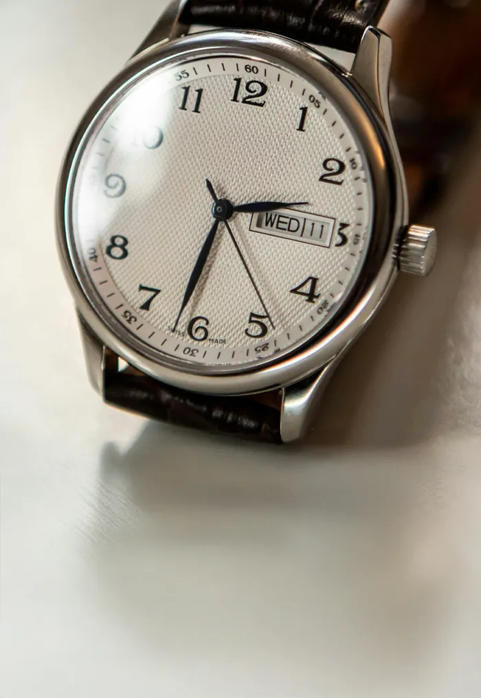 Classic silver watch with a white dial and black leather strap.