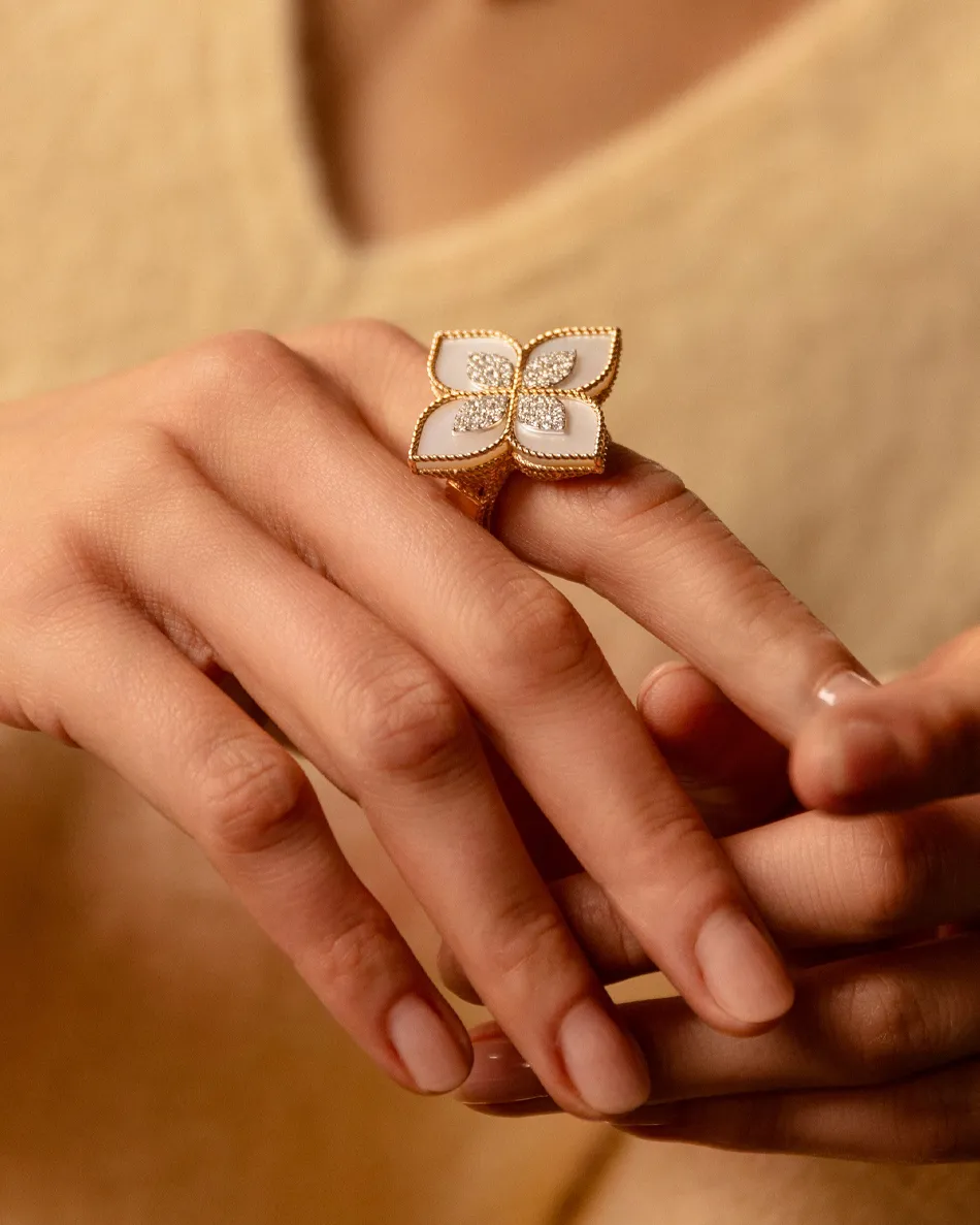 Elegant gold ring with a floral design and sparkling diamonds, worn on a hand.
