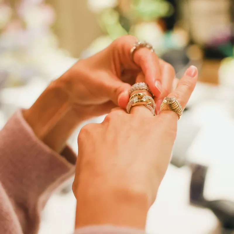 A person trying on multiple fashion rings