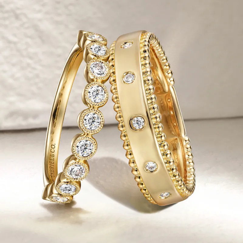 Two elegant gold wedding bands adorned with sparkling diamonds, showcasing intricate designs.