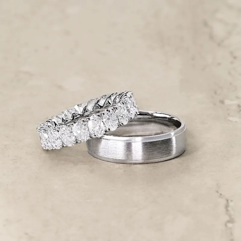 Elegant diamond wedding band and simple silver ring on a neutral surface.