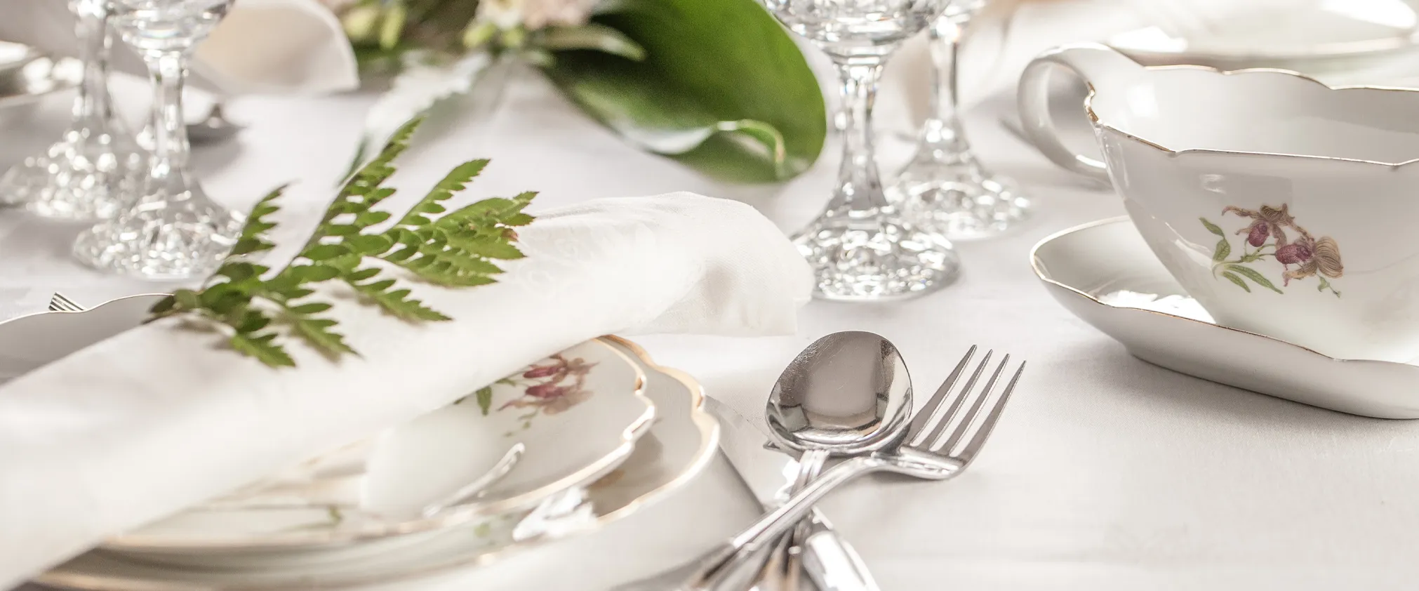 Elegant table setting with fine china, silverware, and a fern accent. Click to Shop All giftware at Tom Cook Jeweler, Inc.