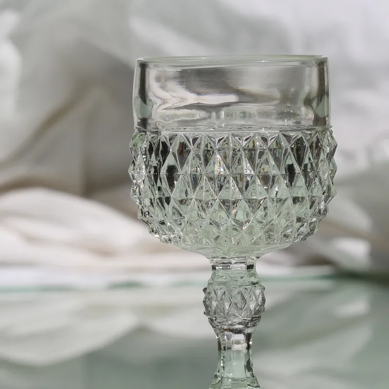 Crystal glass on a reflective surface with soft white fabric in the background. Click to start a project at Tom Cook Jeweler.