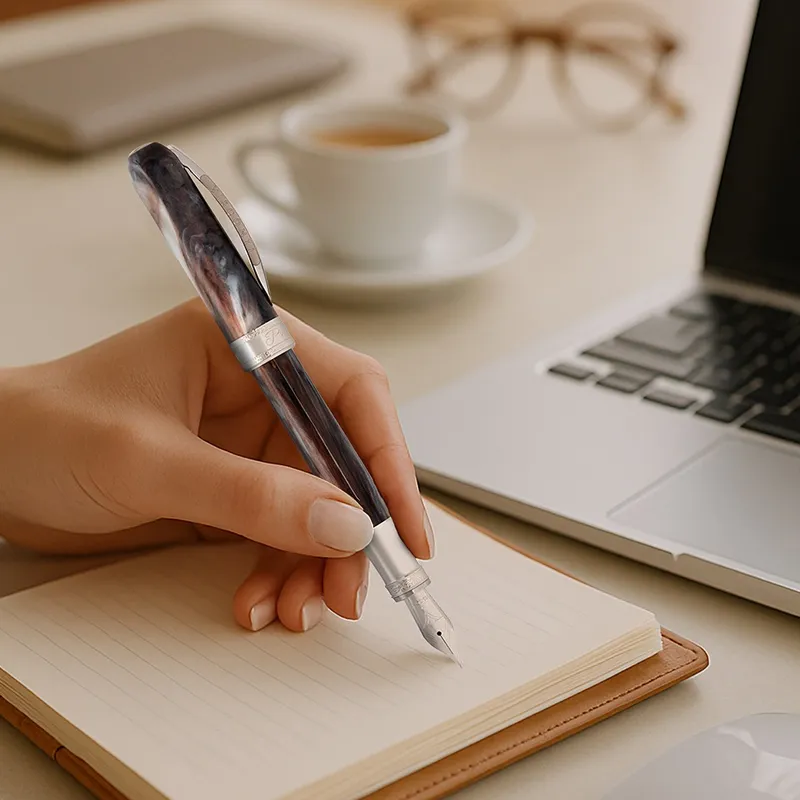 Elegant Visconti fountain pen held above a notebook, with a cup of coffee and laptop in the background. Click to explore Viscont